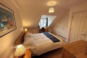 Cozy loft-style room with a central bed, desk, and artwork.