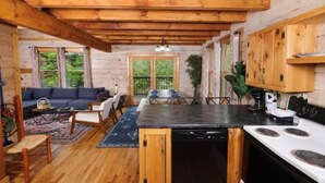 A wooden cabin interior with a kitchen, dining area, and living room.