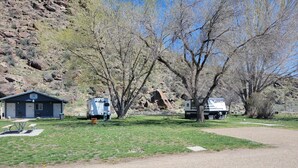 Um camping com um pequeno edifício azul, uma mesa de piquenique e duas casas de recreação.