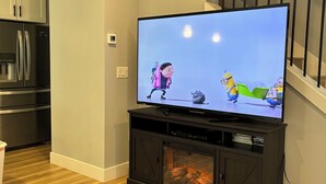 A flat-screen TV on a black entertainment center with a fireplace below it.