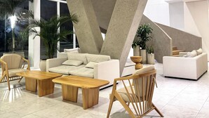 A modern living room with a large sofa, wooden coffee tables, and a unique concrete structure. - Nature and Ocean View Suite With Hot Tub steps to beach in Santa Marta (Santa Marta)