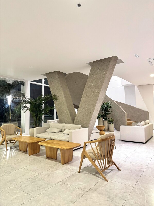 A modern living room with a large sofa, wooden coffee tables, and a unique concrete structure. - Nature and Ocean View Suite With Hot Tub steps to beach in Santa Marta (Santa Marta)
