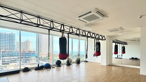 A spacious gym with large windows, ceiling-mounted punching bags, and exercise balls. - Nature and Ocean View Suite With Hot Tub steps to beach in Santa Marta (Santa Marta)
