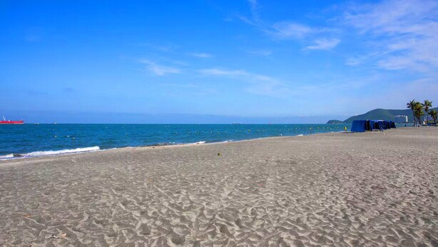 A beach with a clear sky, a red ship in the distance, and a blue tent on the sand. - Nature and Ocean View Suite With Hot Tub steps to beach in Santa Marta (Santa Marta)