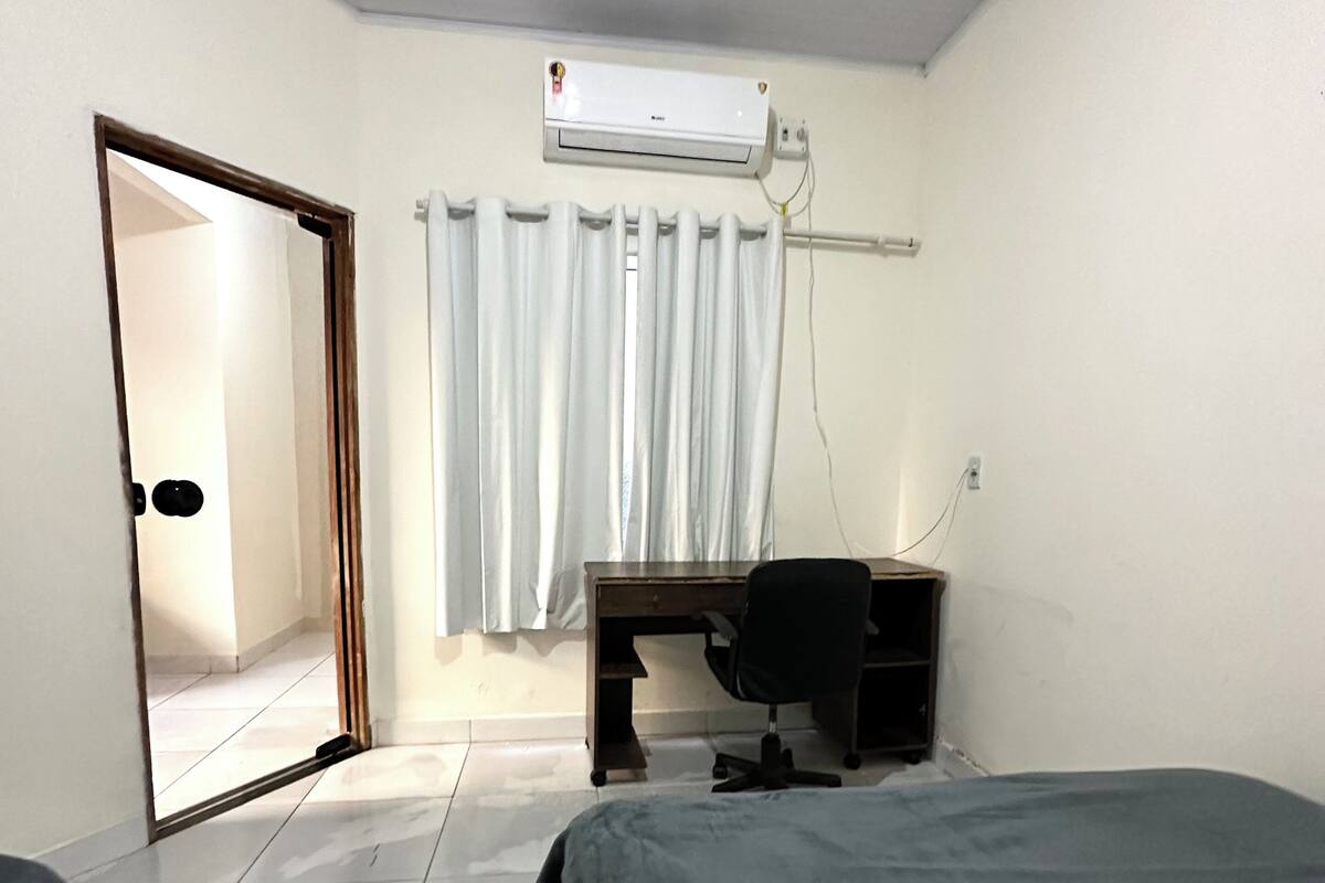 Een hotelkamer met een bed, een bureau, een airconditioner en een deur.