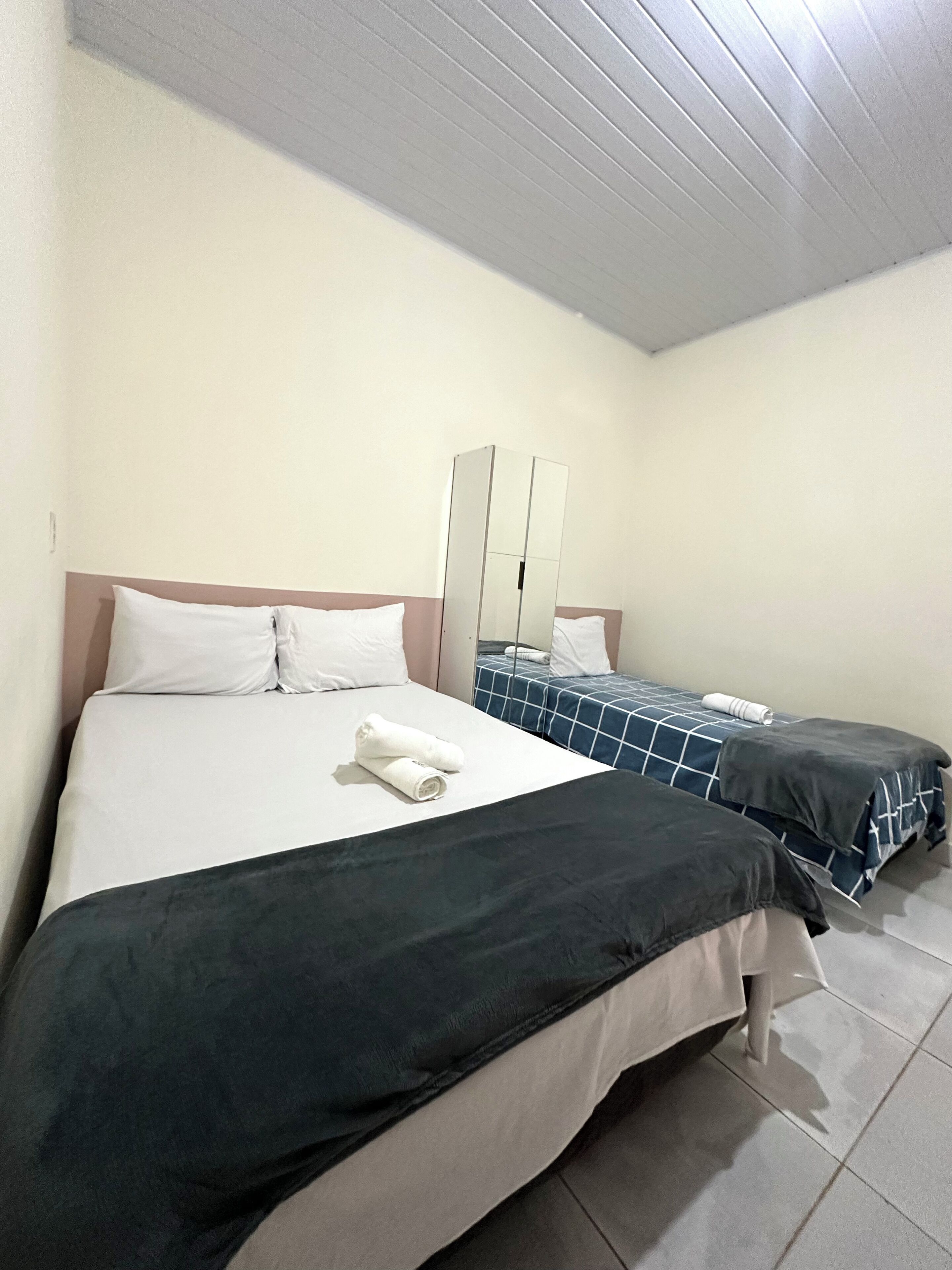 A hotel room with two beds, a large mirror, and a tiled floor.