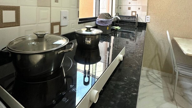 Una cocina con estufa, ollas y ventana.