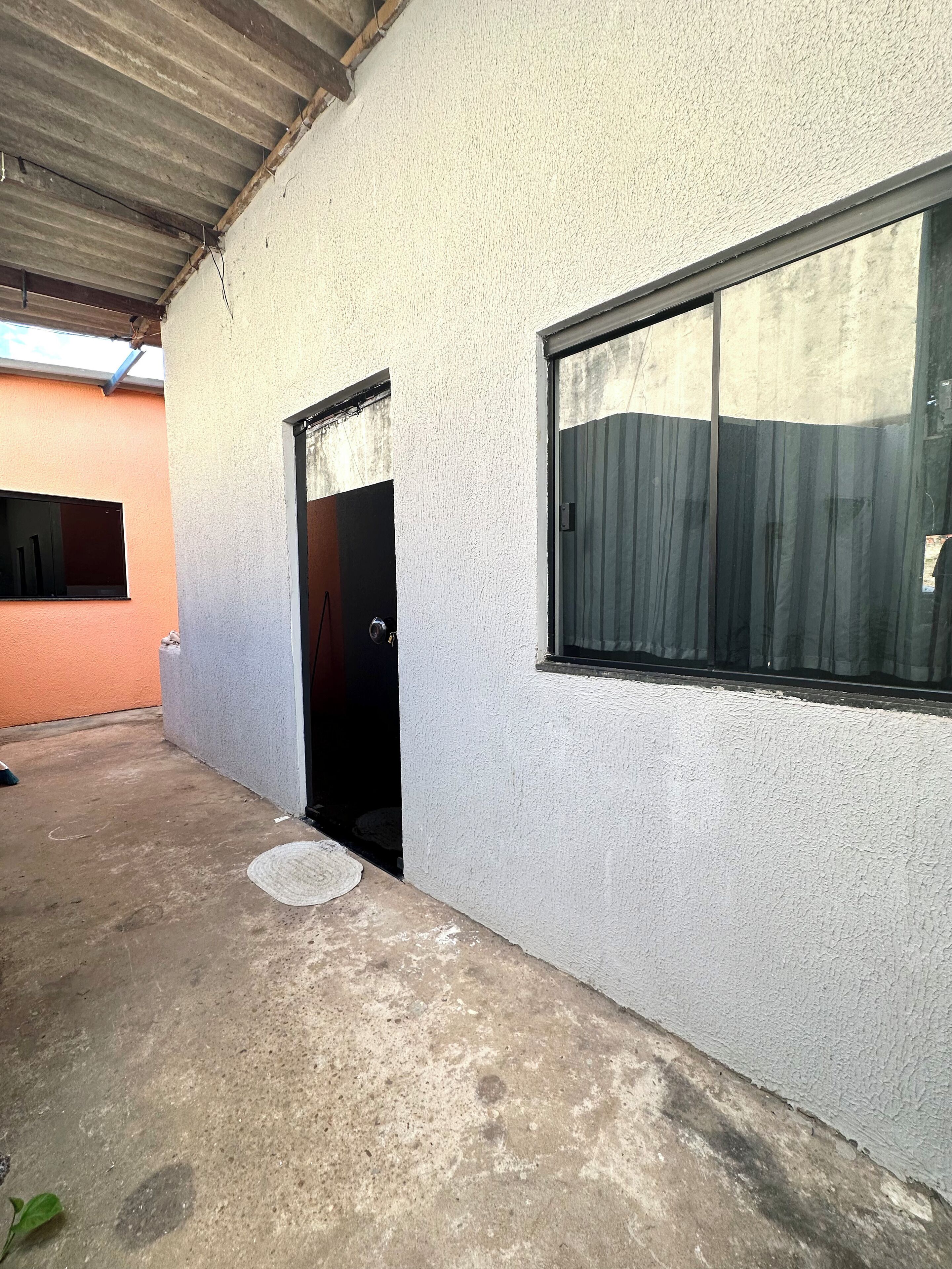 Um edifício com piso de concreto, parede externa branca e porta preta.