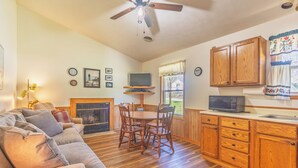 A cozy living room with a fireplace, wooden dining table, and comfortable seating.