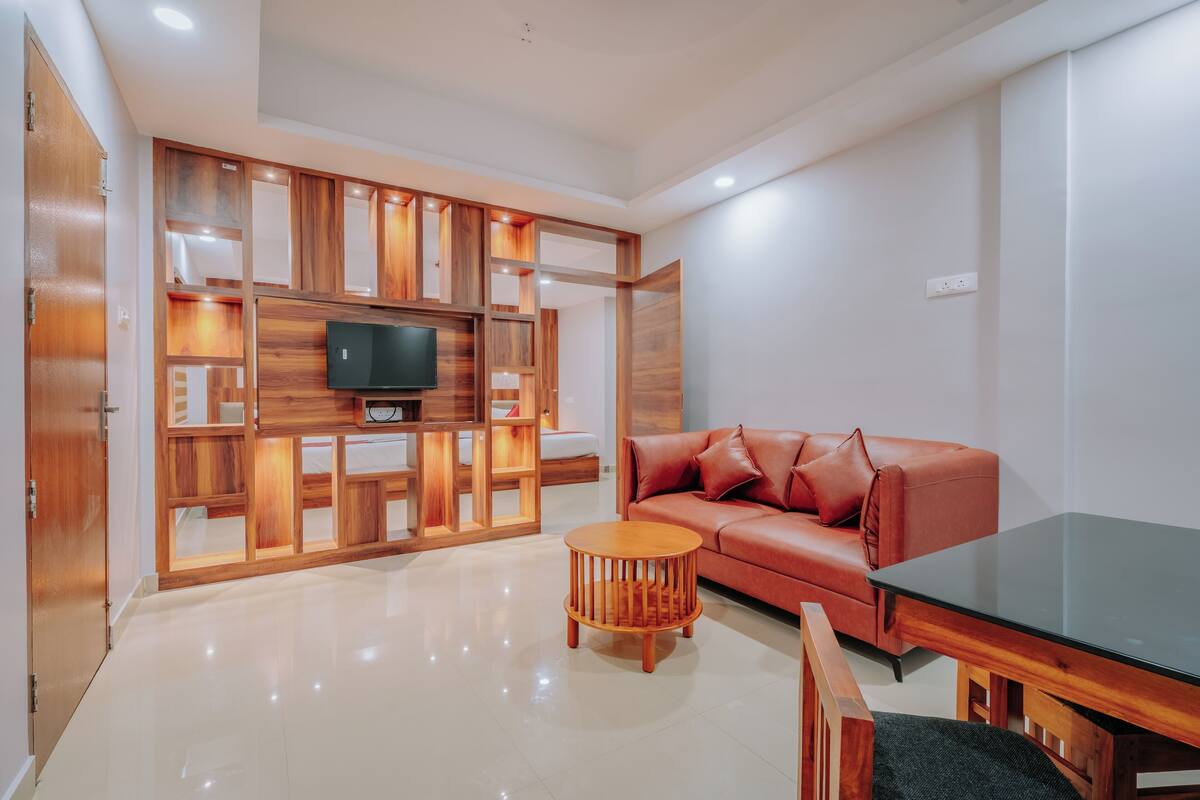 A modern living room with a wooden entertainment unit, a red leather sofa, a glass coffee table, and a wooden dining table.