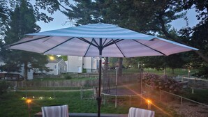 A deck with two striped chairs and a large umbrella. - Charming 3-bedroom house in awesome Urbandale! (Urbandale)