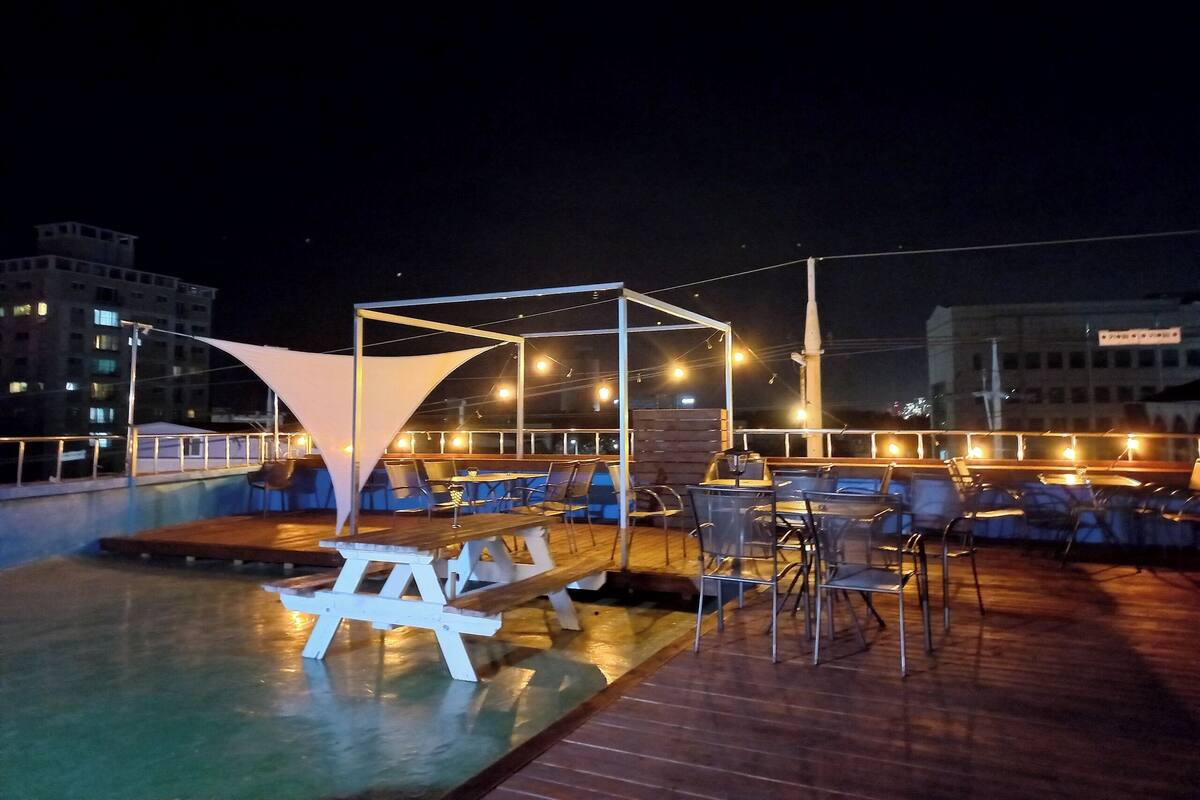 A rooftop pool area with lounge chairs and a wooden deck.