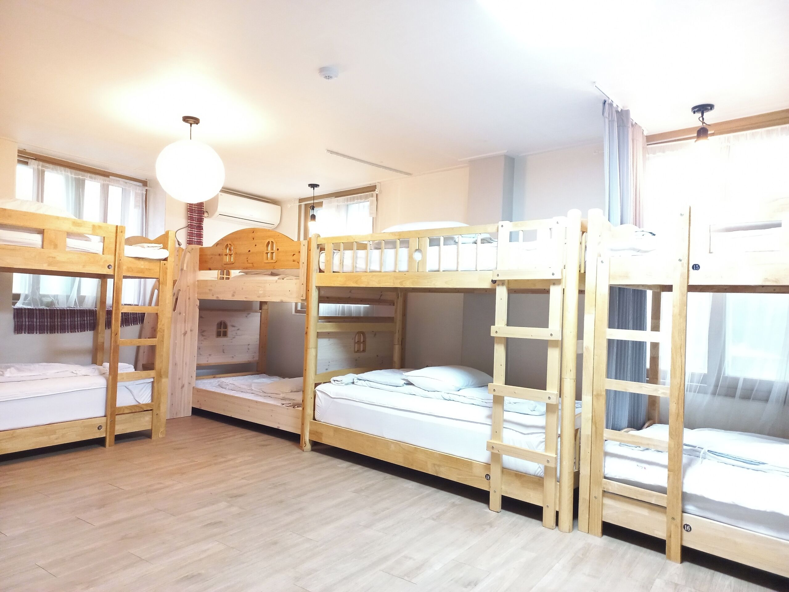 Una habitación con literas, suelo de madera y una lámpara en el techo.
