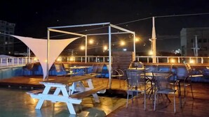 A rooftop bar with tables and chairs, a pool, and a canopy structure. - Youngil Dae Guest house (Pohang)