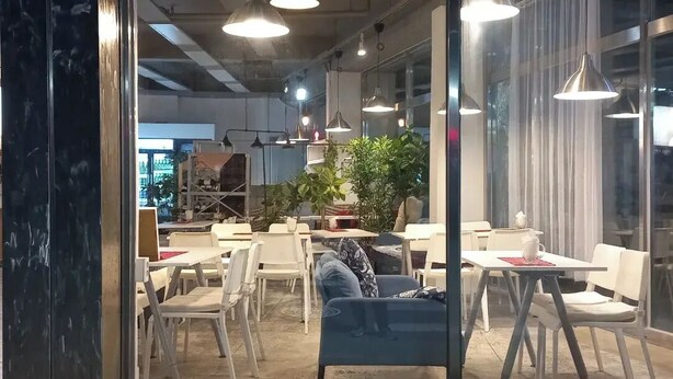 A modern office space with glass walls, multiple tables, chairs, and hanging pendant lights. - Youngil Dae Guest house (Pohang)