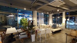 A modern hotel lobby with glass walls, white furniture, and pendant lighting. - Youngil Dae Guest house (Pohang)