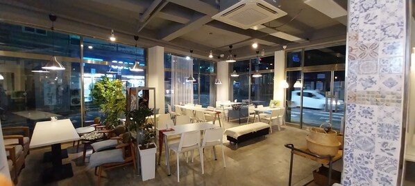 A modern hotel lobby with glass walls, white furniture, and pendant lighting.