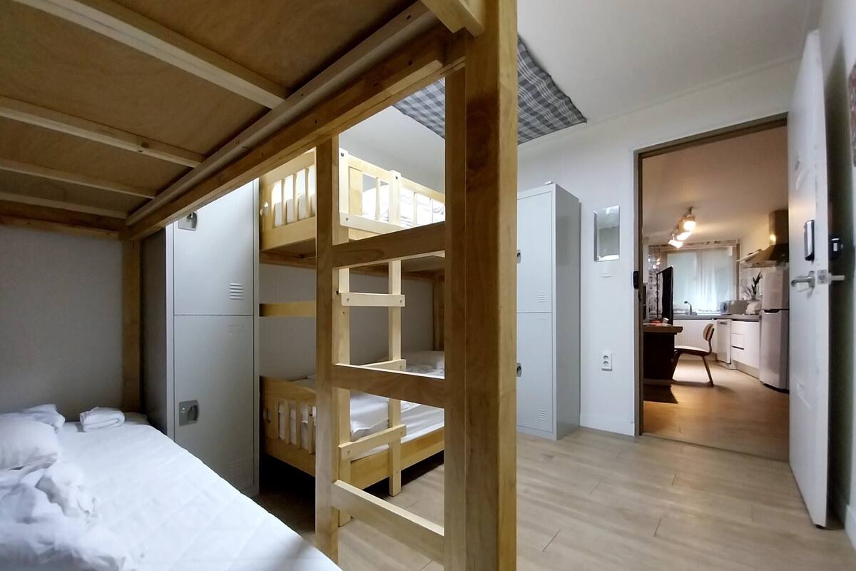 A room with bunk beds, a kitchenette, and a bathroom.
