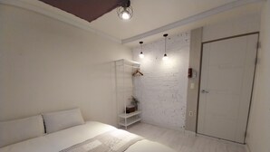 A bedroom with a bed, a wardrobe, a hanging shelf, and a white brick wall. - Youngil Dae Guest house (Pohang)