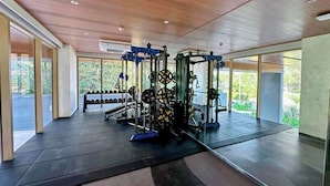 Un gimnasio moderno con diverso equipamiento de levantamiento de pesas, amplias ventanas y un diseño espacioso.