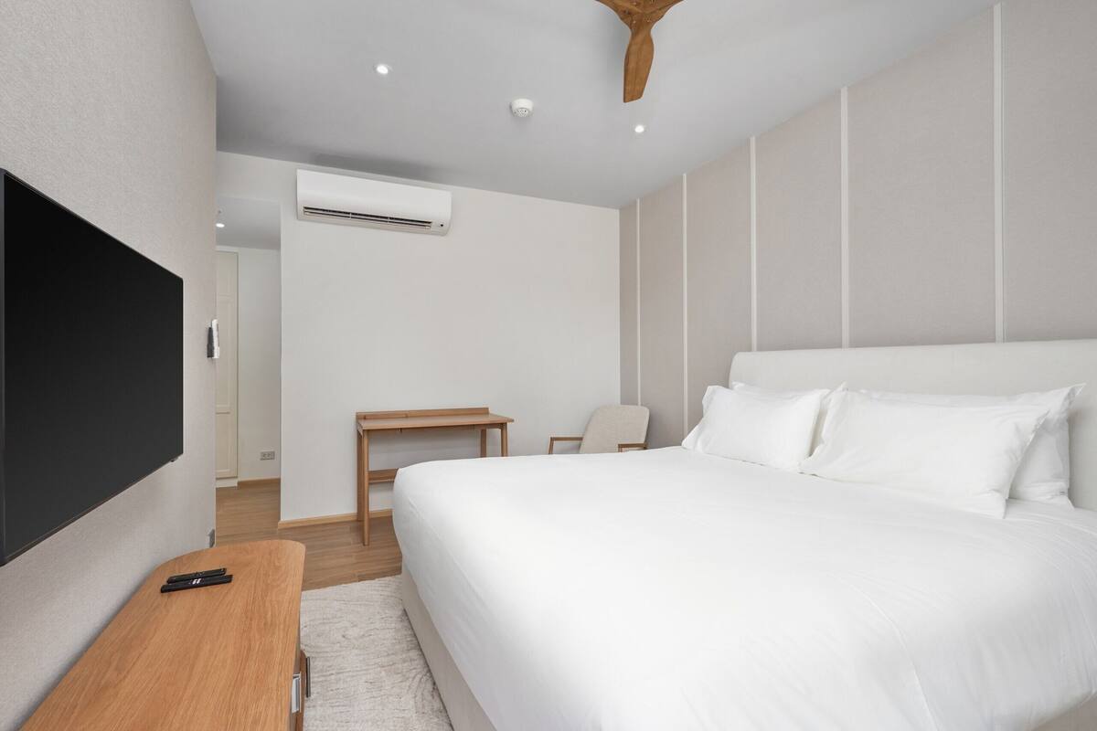 Une chambre d’hôtel moderne équipée d’un grand lit, d’un bureau, d’une chaise et d’un téléviseur à écran plat.