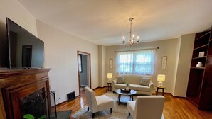 Una sala de estar con chimenea, un sofá, dos sillones, una mesa de centro y un televisor.