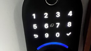 Cerradura electrónica con teclado negro, números iluminados e indicador luminoso azul.