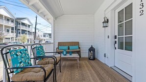 A covered porch with two metal chairs, a bench, and a lantern. - Modern 3BR w/ Backyard, Grill & Outdoor Shower (Ventnor City)