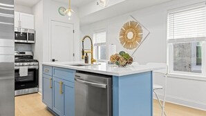 A modern kitchen with a central island, stainless steel appliances, and blue cabinetry. - Modern 3BR w/ Backyard, Grill & Outdoor Shower (Ventnor City)