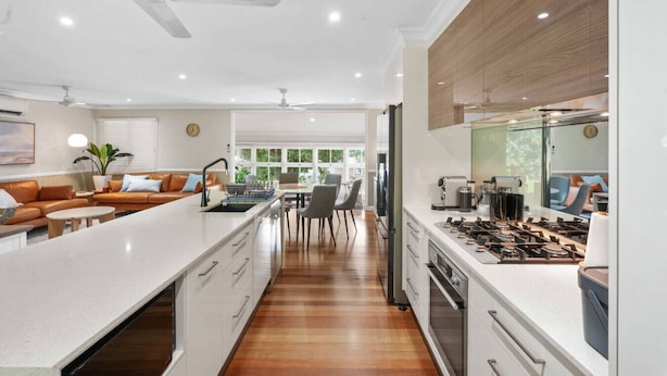 Una cocina moderna con una isla central, armarios blancos y suelo de madera.