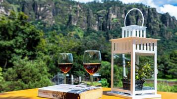 Una mesa con dos copas de vino, un libro y un farolillo con una planta.
