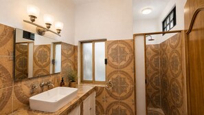 A bathroom with a large mirror, a sink, and a shower area. - Hikuri House (Tepoztlán)