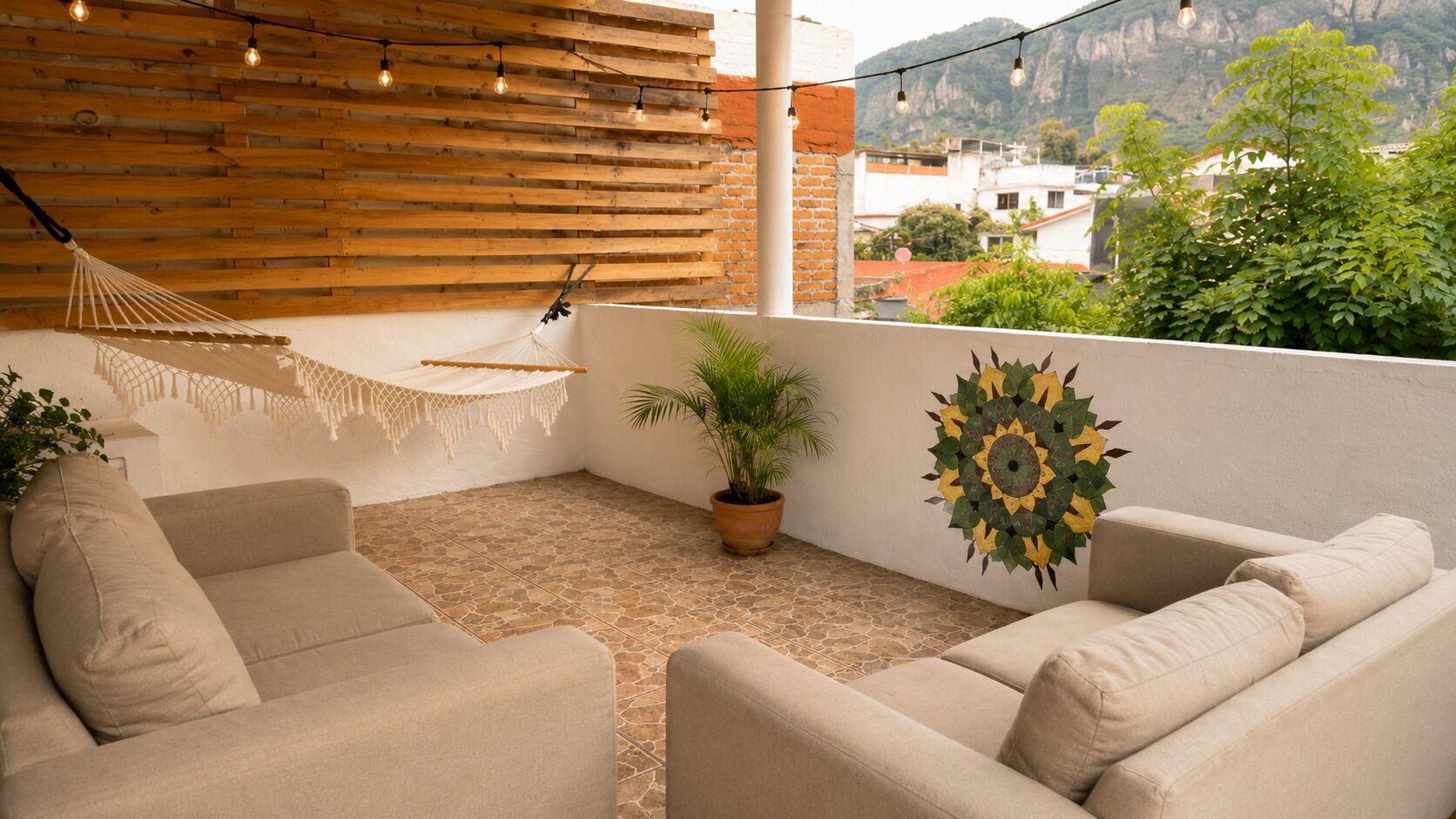 Een balkon met twee beige banken, een hangmat, een plant in pot en decoratieve zonstraal-wanddecoratie.