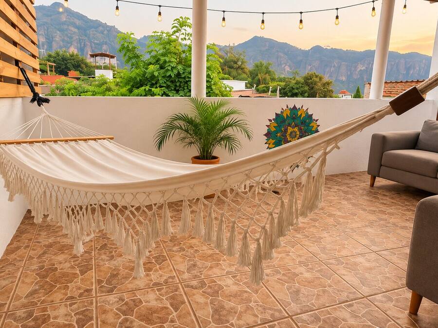 Una hamaca en una habitación con vistas a las montañas, un sofá y una planta en maceta.