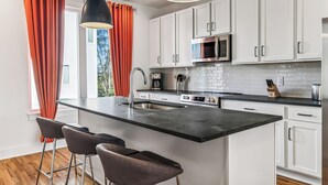 A modern kitchen with white cabinets, a black countertop, and a stainless steel microwave. - Nashville Rooftop Oasis! 8 min Broadway. Sleeps 12 (Nashville)