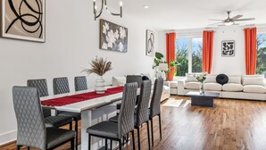 A modern living room with a white sofa, a dining table with grey chairs, and a large abstract painting on the wall. - Nashville Rooftop Oasis! 8 min Broadway. Sleeps 12 (Nashville)
