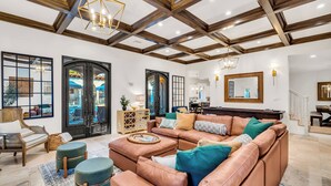A spacious living room with a large sectional sofa, ottomans, and a wooden ceiling. - Full Mediterranean Botanical Garden Estate: 2 Adjacent listings, 9bd 5.5bth EV (Sarasota)