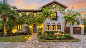 A two-story house with a tiled driveway, a front yard with a fountain, and a garage. - Full Mediterranean Botanical Garden Estate: 2 Adjacent listings, 9bd 5.5bth EV (Sarasota)