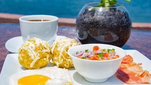 A breakfast tray with eggs, a salad, and a cup of coffee by a pool.