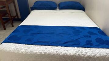 A single bed with a white mattress and blue bedding.