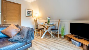 Un salon moderne avec un canapé en cuir, une table à manger avec des chaises, un téléviseur à écran plat et une porte en bois.