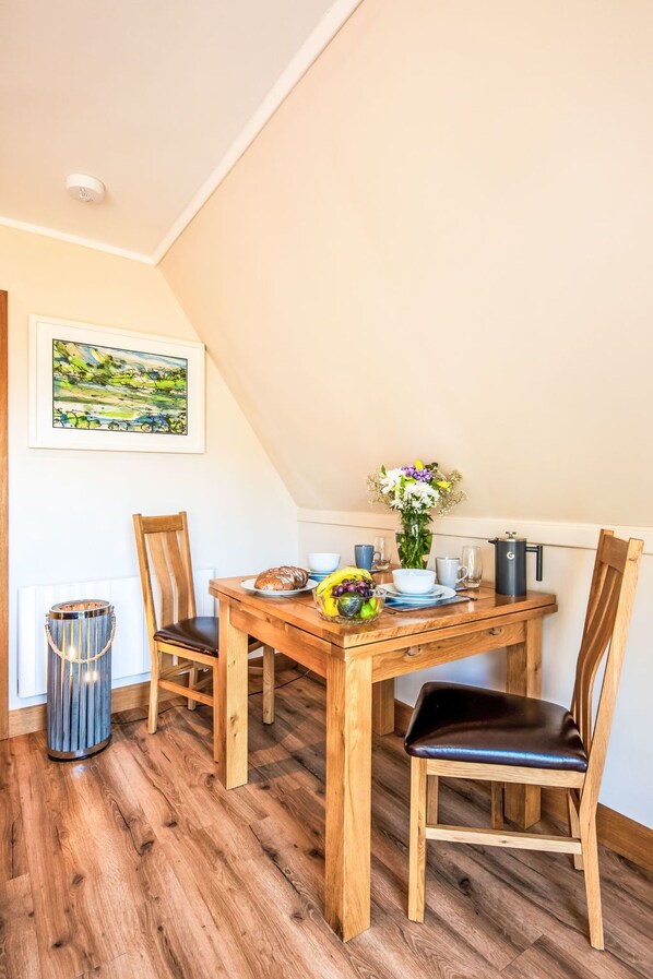 Een eethoek met een houten tafel, stoelen en een bloevas.