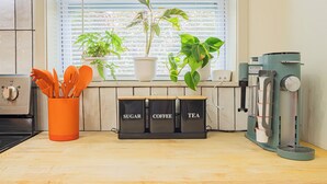 Una cocina con cafetera, una ventana con persianas y una planta.