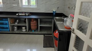 Une cuisine équipée d’une cuisinière à gaz, d’un évier, d’une fenêtre et d’une porte.