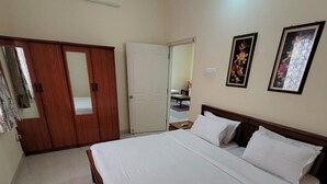 Une chambre à coucher avec un grand lit, une armoire en bois et deux tableaux encadrés accrochés au mur.