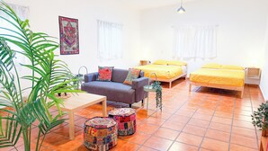 Une pièce comprenant un canapé, deux lits, une table et une plante en pot.