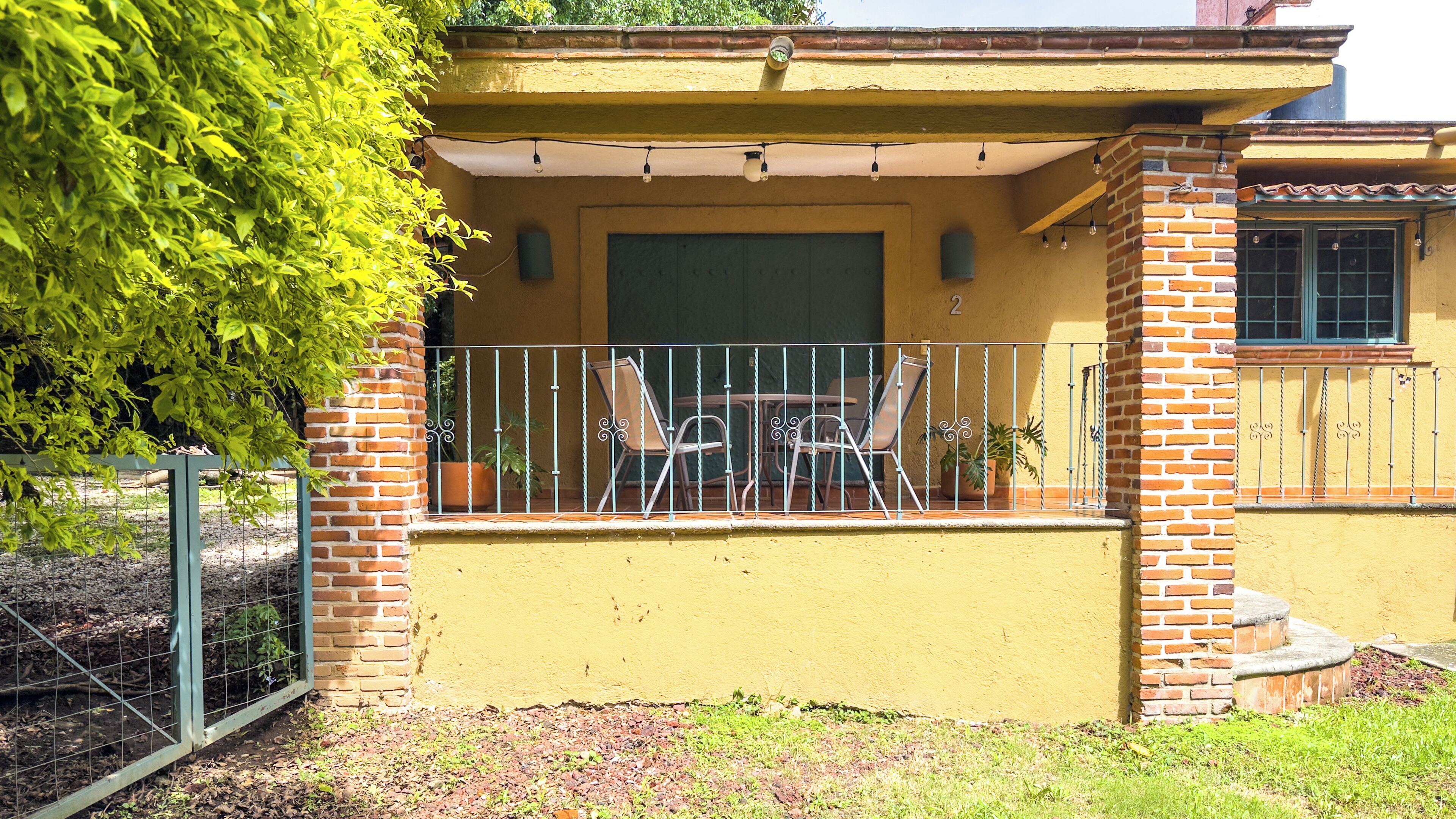A house with a covered porch, outdoor seating, and a brick wall.