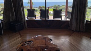Ein Zimmer mit Holzboden, Meerblick und einem Balkon mit Sitzgelegenheiten.