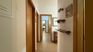 Un pasillo con puertas de madera, un espejo y estanterías en la pared.