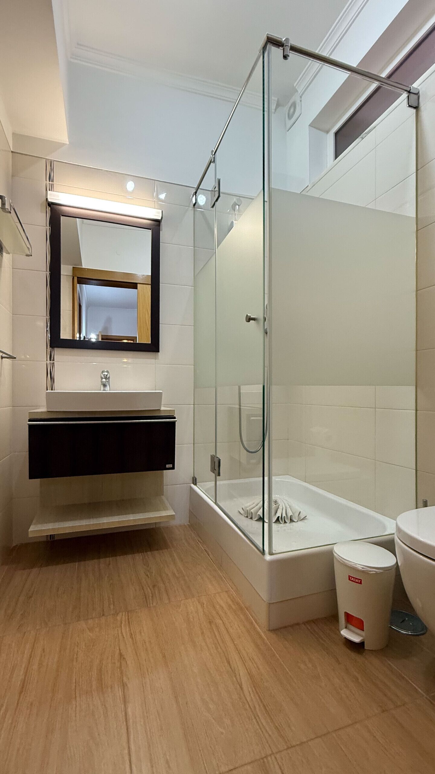 A modern bathroom with a glass-enclosed shower, a vanity with a mirror, and a toilet.